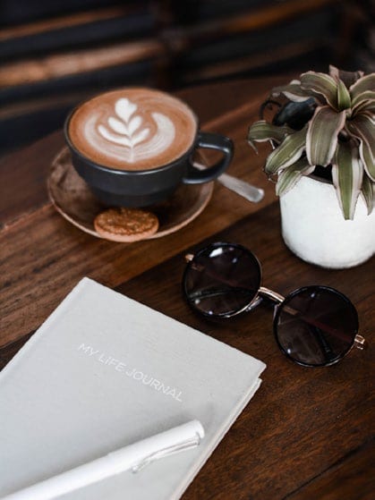 An Amazonia coffee and journal on a wooden table.