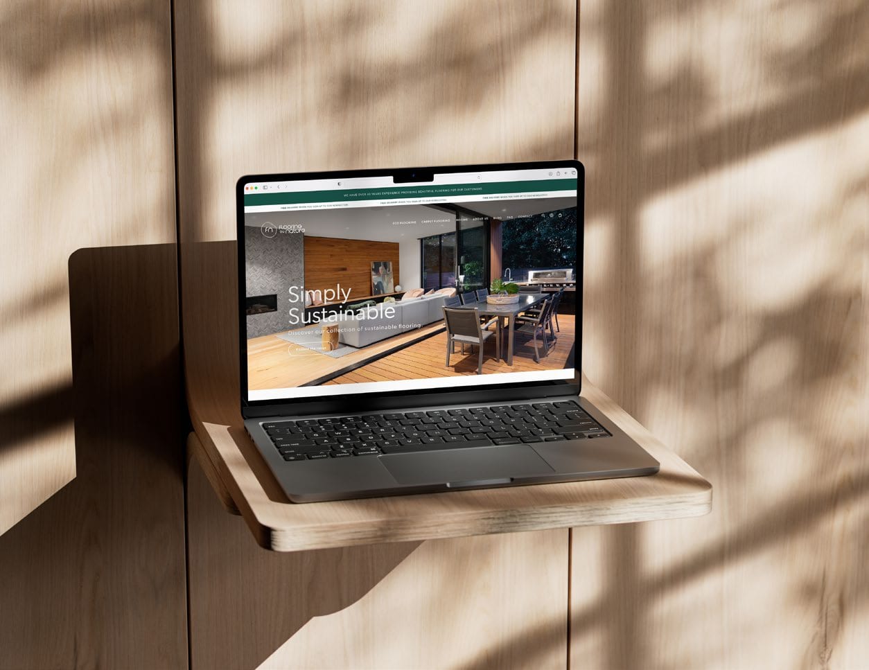 Flooring by Nature website on a laptop, mounted on a wooden wall.