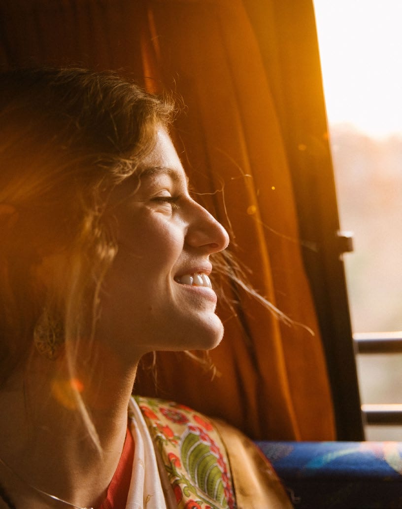 A smiling woman by a window in warm light, from the Holmes & Partners brand shoot