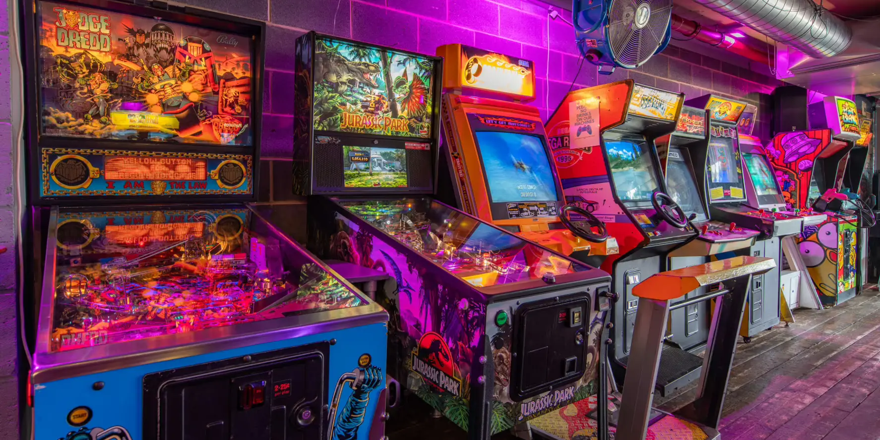 Rows of retro pinball and arcade machines lit by neon inside Four Quarters, Newcastle.