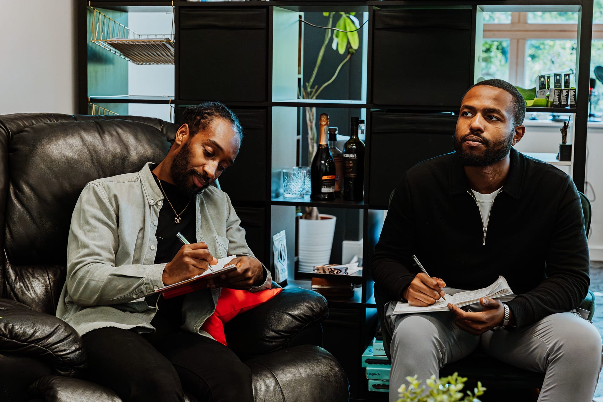 Two 21 Degrees colleagues taking notes together on a sofa in a relaxed lounge workspace.