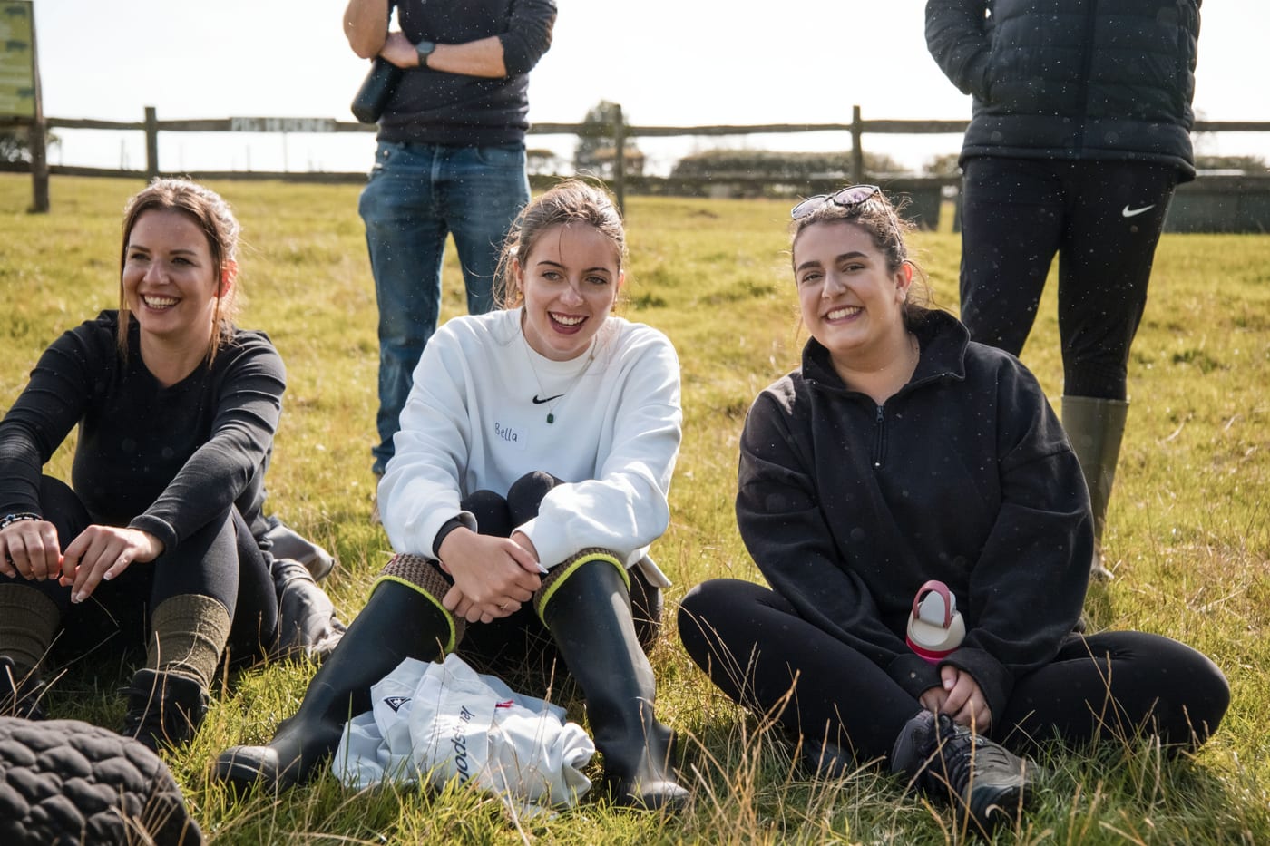 Members of the 21 Degrees team sitting and laughing together on the grass at an outdoor team day.